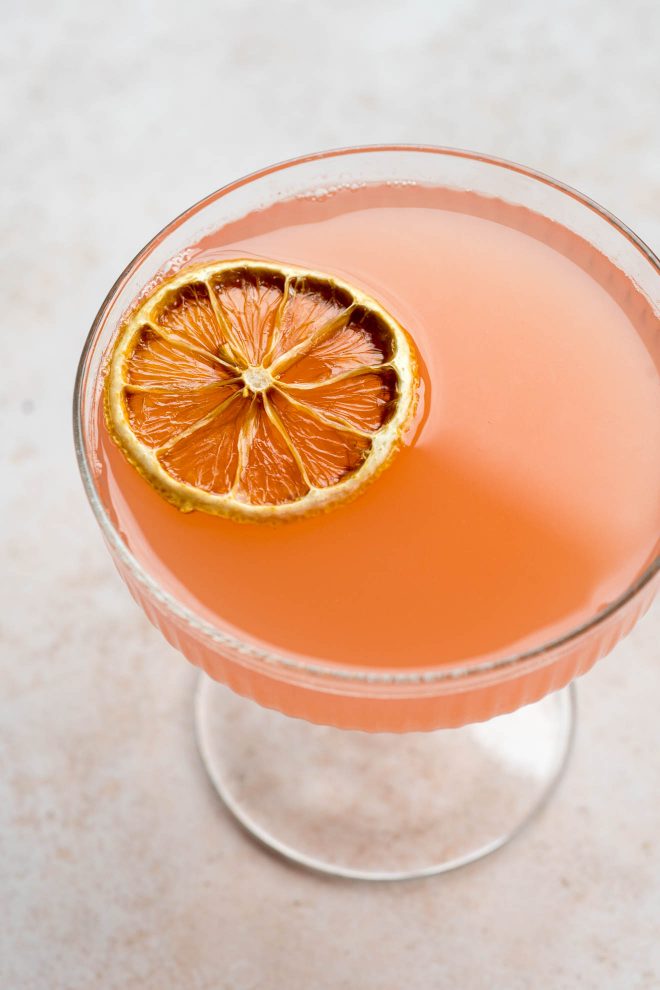 Close up of an orange cocktail with a dried orange slice.