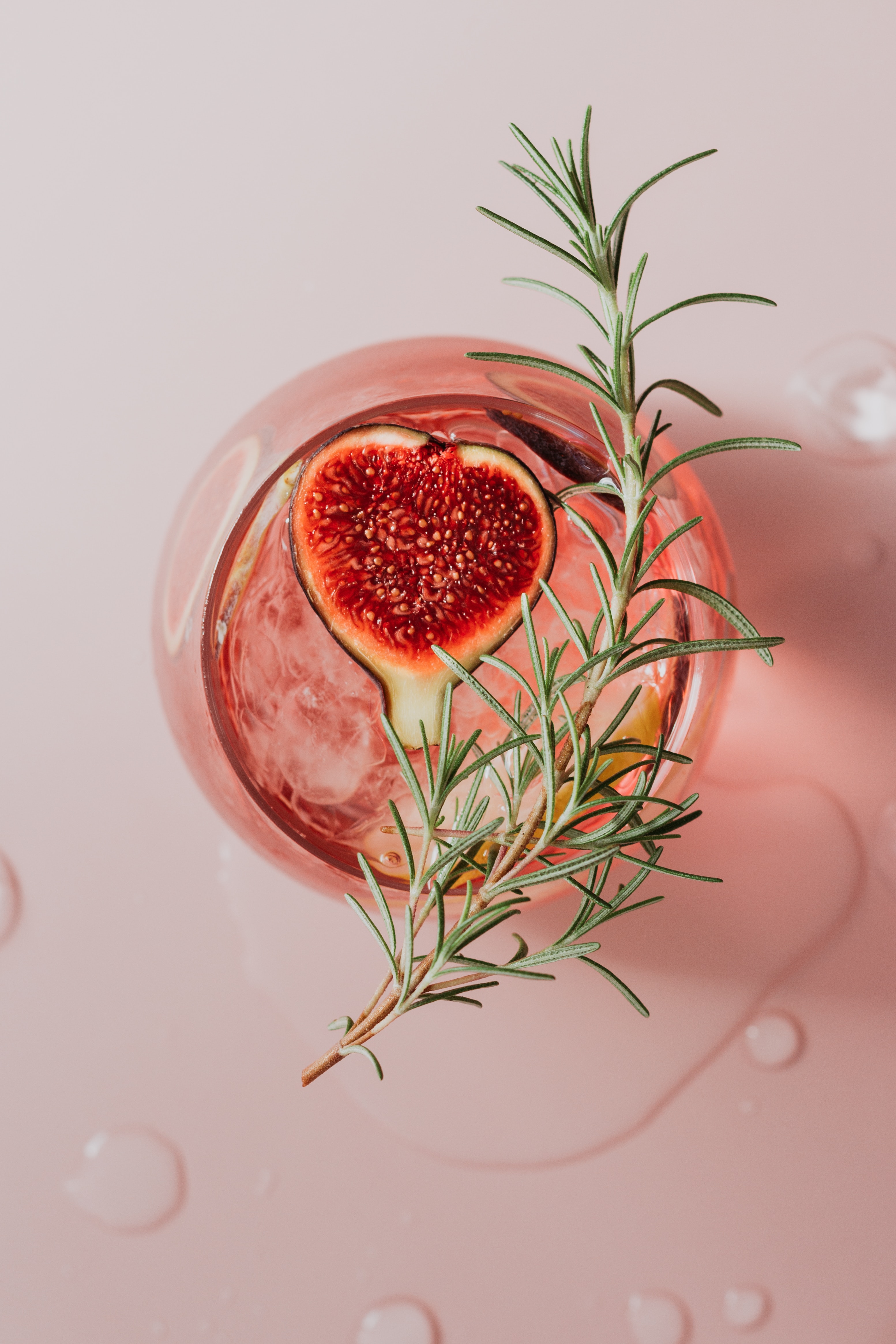Top view of a fig cocktail with a rosemary garnish.