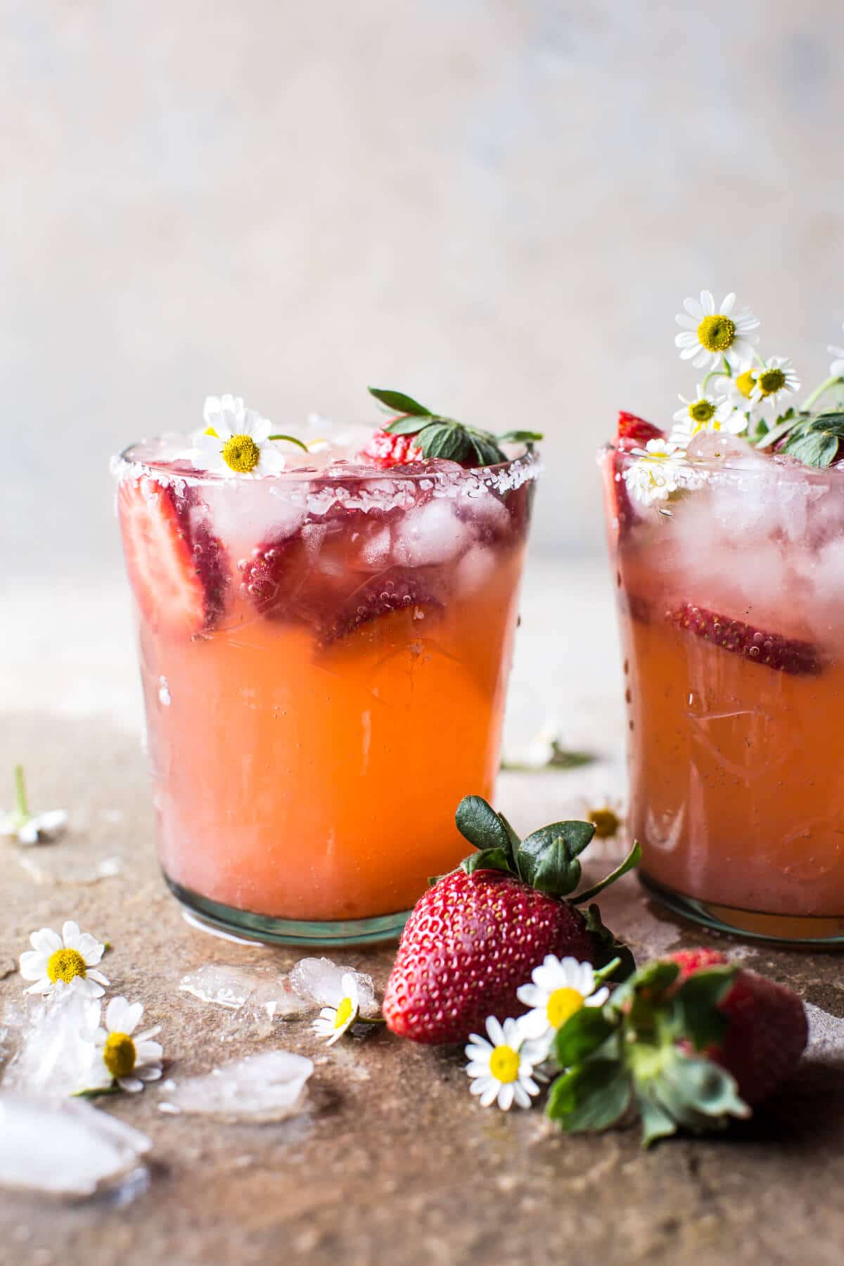 2 strawberry cocktails on a surface with small flowers.
